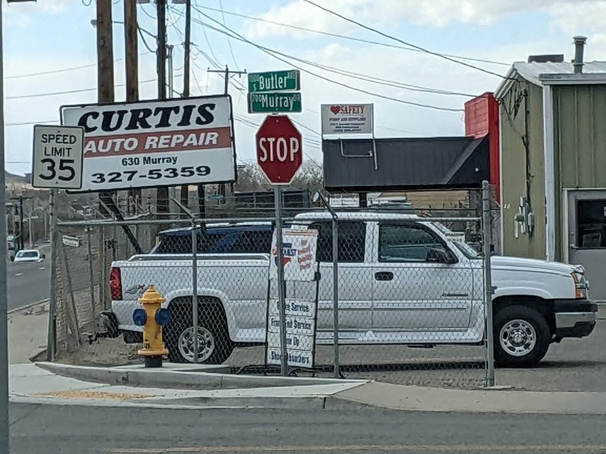 Curtis Auto Repair street sign at 630 Murray Dr, Farmington, with the shop and a customer truck behind the fence